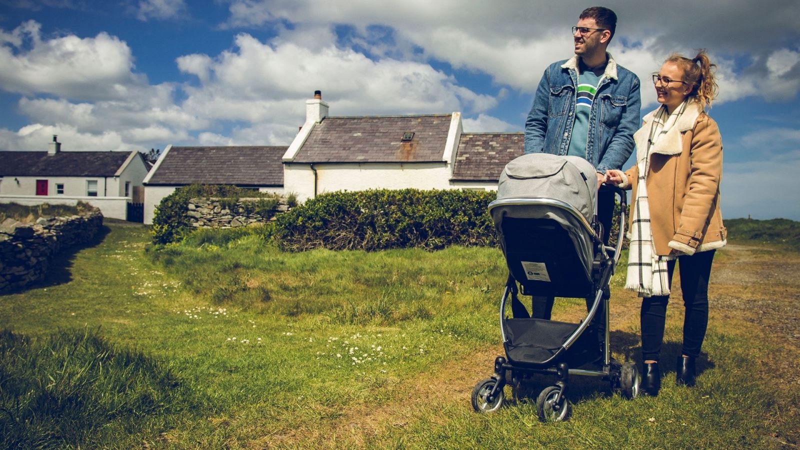 Young man and woman with baby in pram enjoying a stroll around Kearney Village